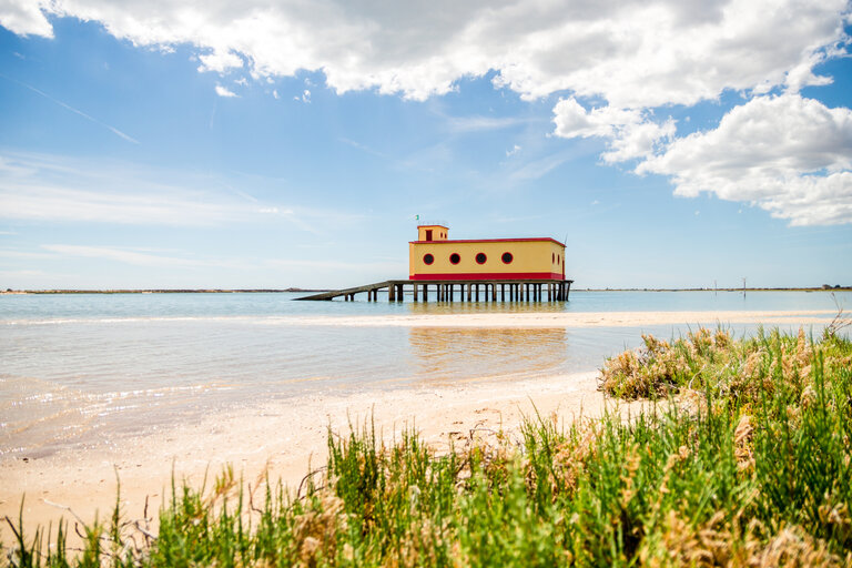 Vue sur la plage ensoleillée du bâtiment historique des sauveteurs de Fuseta, parc naturel de Ria Formosa, Portugal