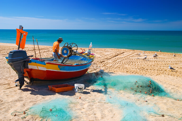 Pécheur en train de remonter les filets sur son bateau sur une plage d'Armacao de Pera en Algarve dans le sud du Portugal