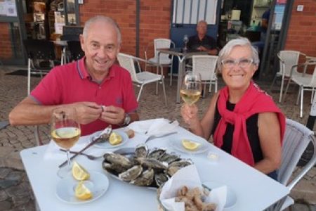 Photo de Gigi et Jean-Pierre, propriétaires de Marina Gigi et Casa Gigi, en train de manger des huitres au marché d'Olhão. Location de vacances à Olhão dans le sud du Portugal